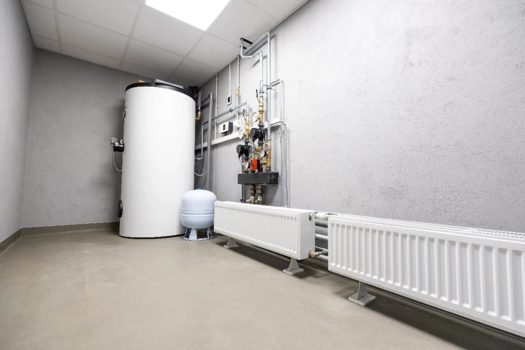 Heizraum mit Warmwasserspeicher, Verteiler und Heizkörper an der Wand